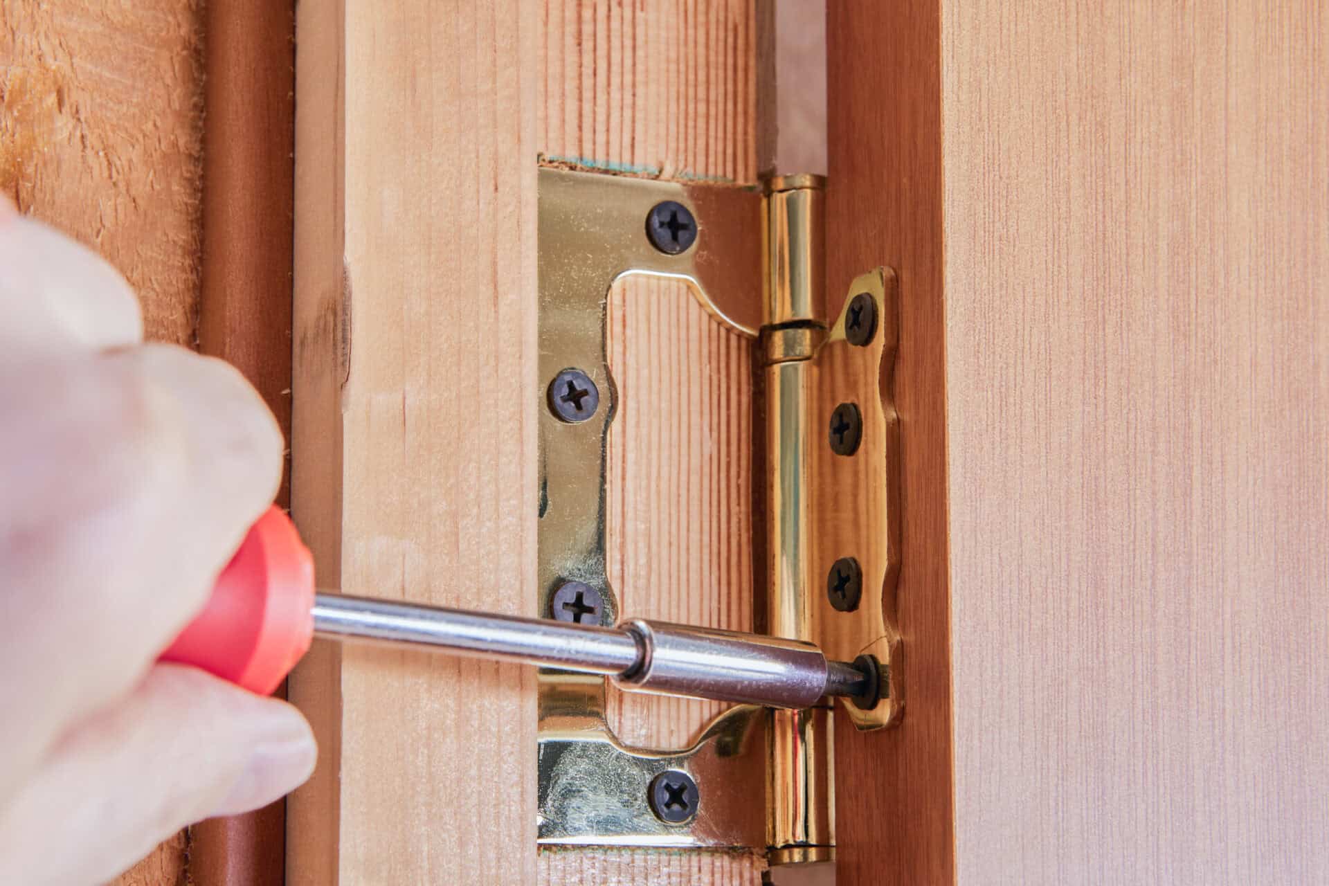 Carpenter fitting a hinge to a timber door and frame